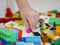 Little baby`s hand picking / choosing a piece of colorful interlocking plastic bricks
