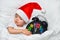 Little baby sleeping on white linen in the Santa hat and alarm show five minutes to eleven