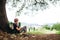 Little backpacker traveler rest under tree on country road