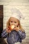 Little baker. Child eating bread bun on white brick wall