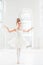 Little ballerina girl in a tutu. Adorable child dancing classical ballet in a white studio.