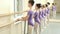 Little ballerinas in purple leotards training at barre.