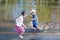 Little barefoot girl with boy laugh and run in water of pond