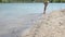 Little barefoot girl runs along the sandy shore of the lake