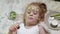 Little beautiful beautiful girl is making cucumber masks at home and eating vegetables