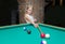 Little beautiful blond girl learns to play billiards, pool, snooker, Russian pyramid in kid`s club