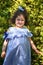 Little beautiful curly girl is looking at the photographer in the park on a sunny day.