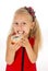 Little beautiful female child with long blonde hair and red dress eating sugar donut with toppings delighted and happy