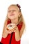 Little beautiful female child with long blonde hair and red dress eating sugar donut with toppings delighted and happy