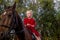 A little beautiful girl in a barnyard walks with a horse,