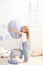 Little beautiful girl in casual clothes stands on the background of a decorative balloon. The child plays in the children room. Th