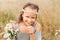 A little beautiful girl collects daisies in the meadow