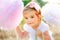 Little beautiful girl in festive dress is light between two huge paper pompoms