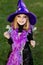 Little beautiful girl with halloween witch costume smiling and have colored candy