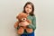 Little beautiful girl hugging teddy bear relaxed with serious expression on face