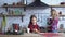 Little beautiful girl with long brown hair eating cookies with tea on the kitchen table and young mother make coffee