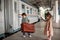 Little beautiful girl in retro dress says goodbye at the station with a little boy in vintage clothes with retro suitcase