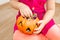 Little beautiful girl sitting with a pumpkin with candies in her hands, on Halloween.