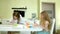 Little beautiful red-haired girl and mother paints with paintand brush sitting at table