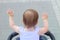 little, beautiful, smiling, cute redhead baby in a sleeveless shirt in a pram out-of-doors raises his hands up looking forward