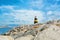 Little beautiful white, yellow and black lighthouse standing over the big stones at the pier of Benalmadena port, panoramic view