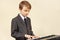 Little beginner musician in a suit playing electronic synth