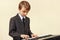 Little beginner musician in suit playing the synthesizer