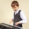 Little beginner pianist in a suit playing digital piano