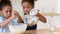 Little biracial kids make dough baking together in kitchen