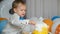 The little birthday boy touches the cream on the birthday cake with his finger in a funny way