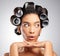 A little bit of hair inspiration. Studio shot of an attractive young woman posing with curlers in her hair against a