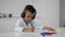 Little Black Boy Wearing Wireless Headphones Drawing With Colorful Pencils At Home