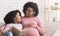 Little black girl and her pregnant mom enjoying reading book together