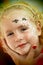 Little blond blue eyed girl face painting is smiling