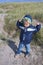 Little blond boy in blue windcheater, tensioning his arms happy, for fighting against the North Wind in sand dunes in Scandinavia