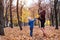 Little blond boy gives his pregnant mother yellow leaf. Autumn park on the background