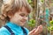 Little blond boy holding bloom leaves outdoors