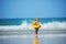 Little blond boy with inflatable yellow duck over sea waves