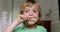 Little blond boy learning brushing his teeth