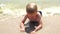 Little blond boy lying on the sand in the water on the beach. Slow motion.