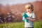 Little blond boy play soap bubbles gun stand in the field