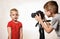 Little blond boy is ready to give the interview, boy takes it on video camera. Young video blogger. White background