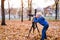 Little blond boy shoots with a large SLR camera on a tripod. Photo session in the autumn park