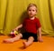 Little blond boy sitting on the floor and holds colored cube