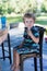 Little blond boy sitting on high chair in cafe with cocktail