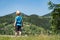 Little blond boy stands on mountains background. Travel with children. Back view