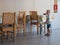 Little blond boy of three years old in a T-shirt and shorts with a mug of tea alone in the dining room