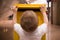 A little blond boy in a white t-shirt puts a letter into a yellow postbox. Sending post to a friend at the post office