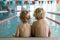 Little blond boys in a pool under the lights with a blurry background