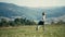 Little Blond Child Running with a Badminton Racket Across a Mountain Meadow